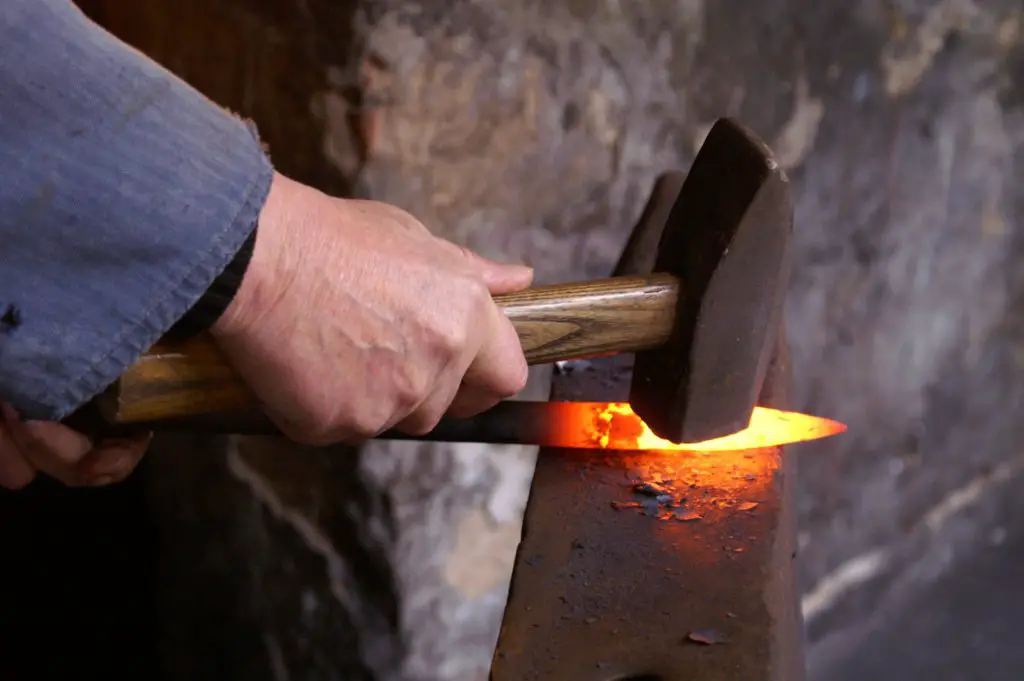 Forging of metal prick with hammer to give it shape before it solidifies.